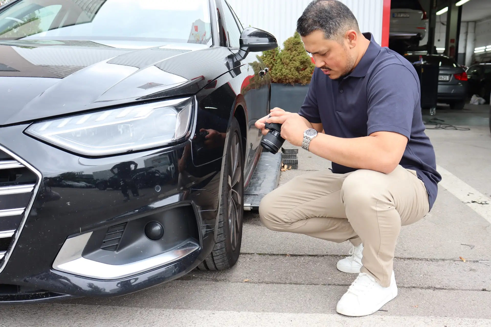 Sobeir Esmaty dokumentiert einen Fahrzeugschaden mit der Kamera bei Tageslicht.